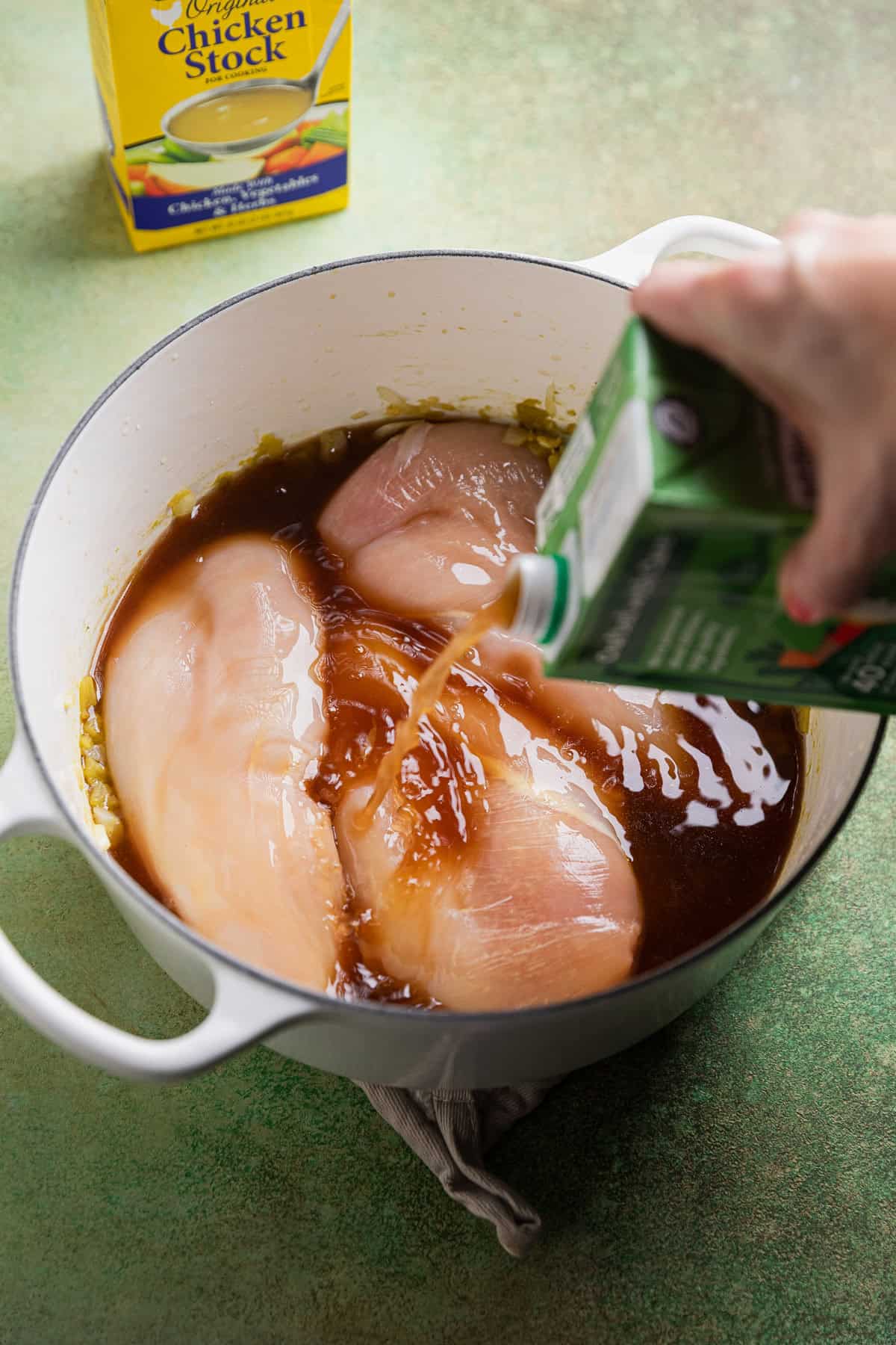 Chicken breasts in soup pot with broth.