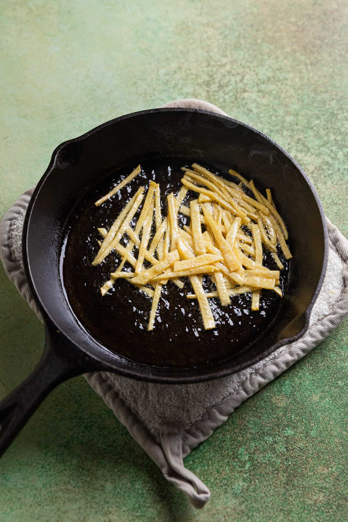 Frying tortilla strips in oil.