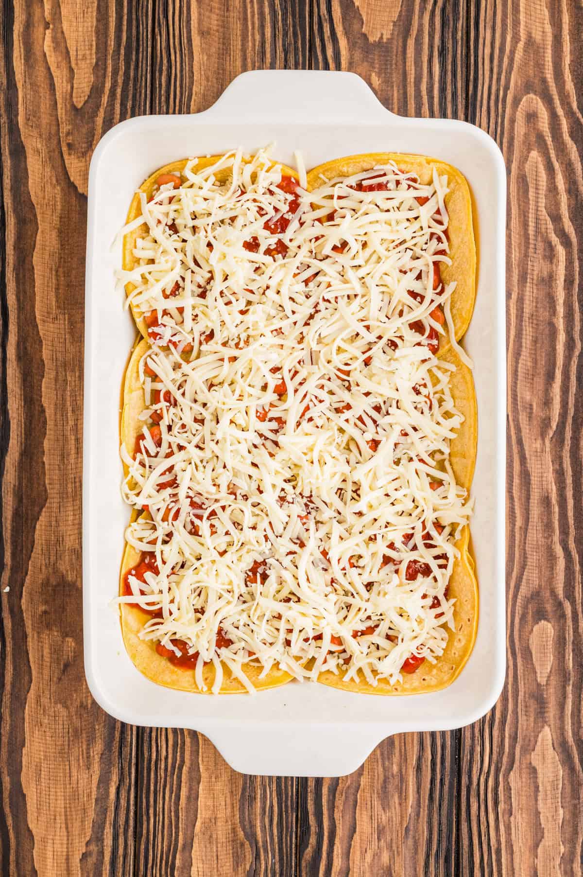 Cheese layered over beans and salsa in a baking dish.