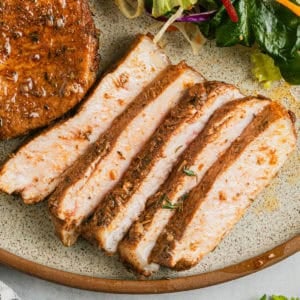 Air fryer honey garlic pork chops sliced on a plate.
