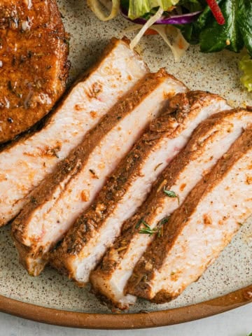 Air fryer honey garlic pork chops sliced on a plate.