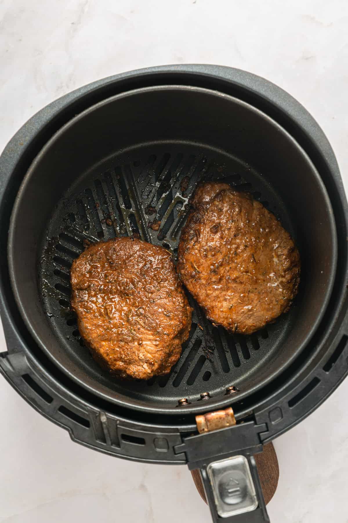 Boneless marinated pork chops cooked on one side in the air fryer basket.