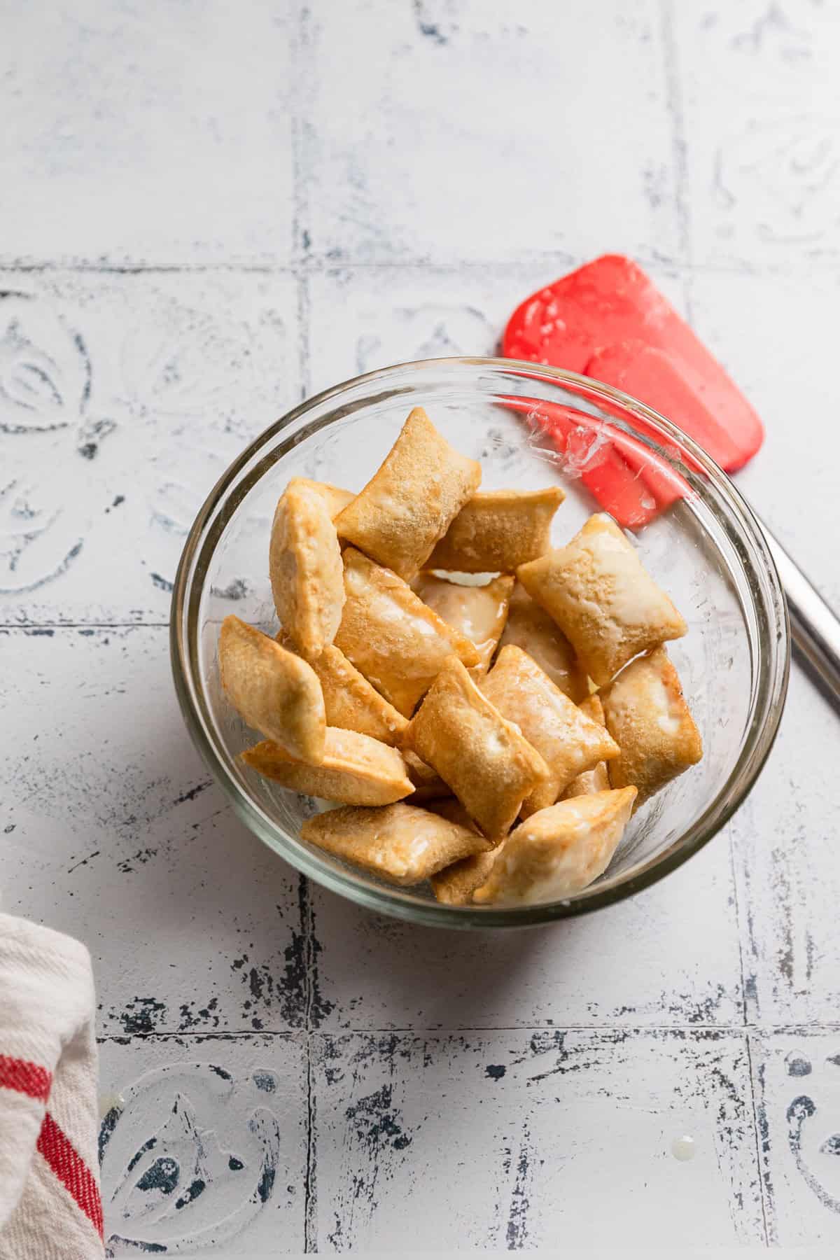 Tossing frozen pizza rolls with oil or butter.