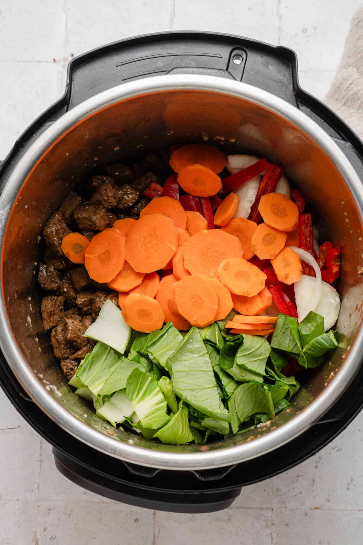 Adding raw vegetables to pot.