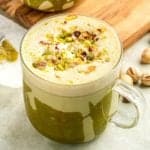 A pistachio latte in a clear mug.