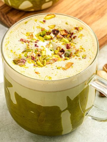 A pistachio latte in a clear mug.