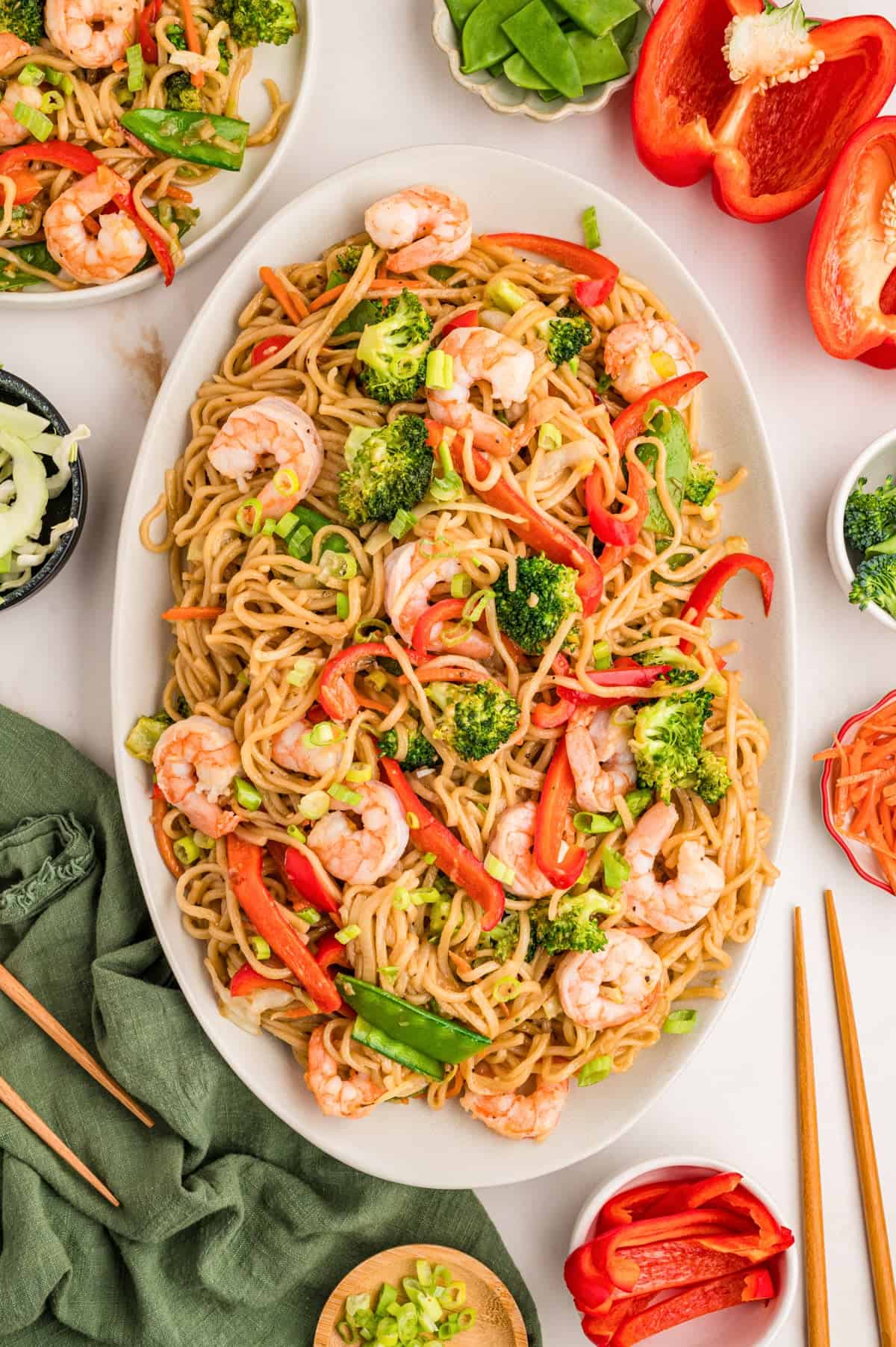 A platter of shrimp stir fry made with lo mein noodles and vegetables.