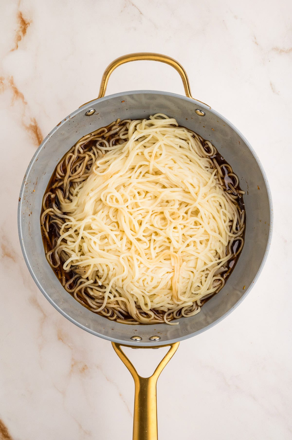 Cooked lo mein with stir fry sauce in skillet.