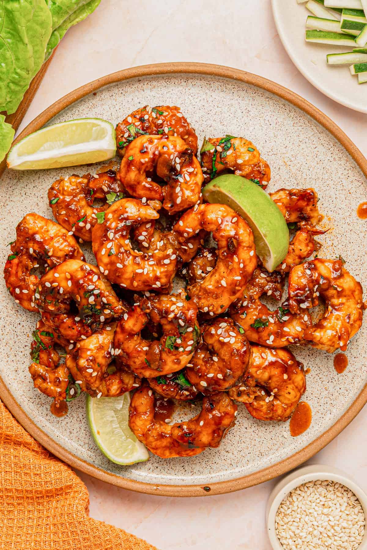 A plate with sweet and spicy shrimp and lime wedges.