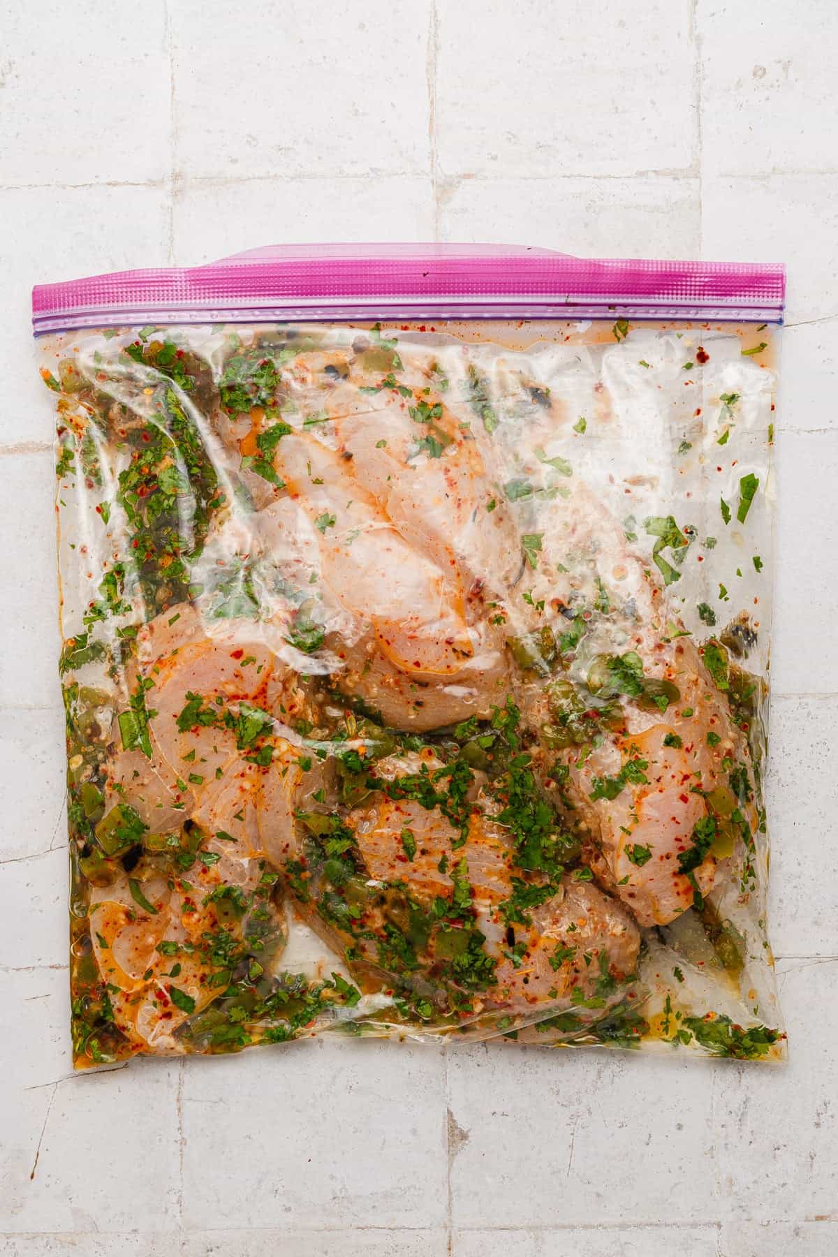 The chicken breasts in the marinade in a plastic bag.